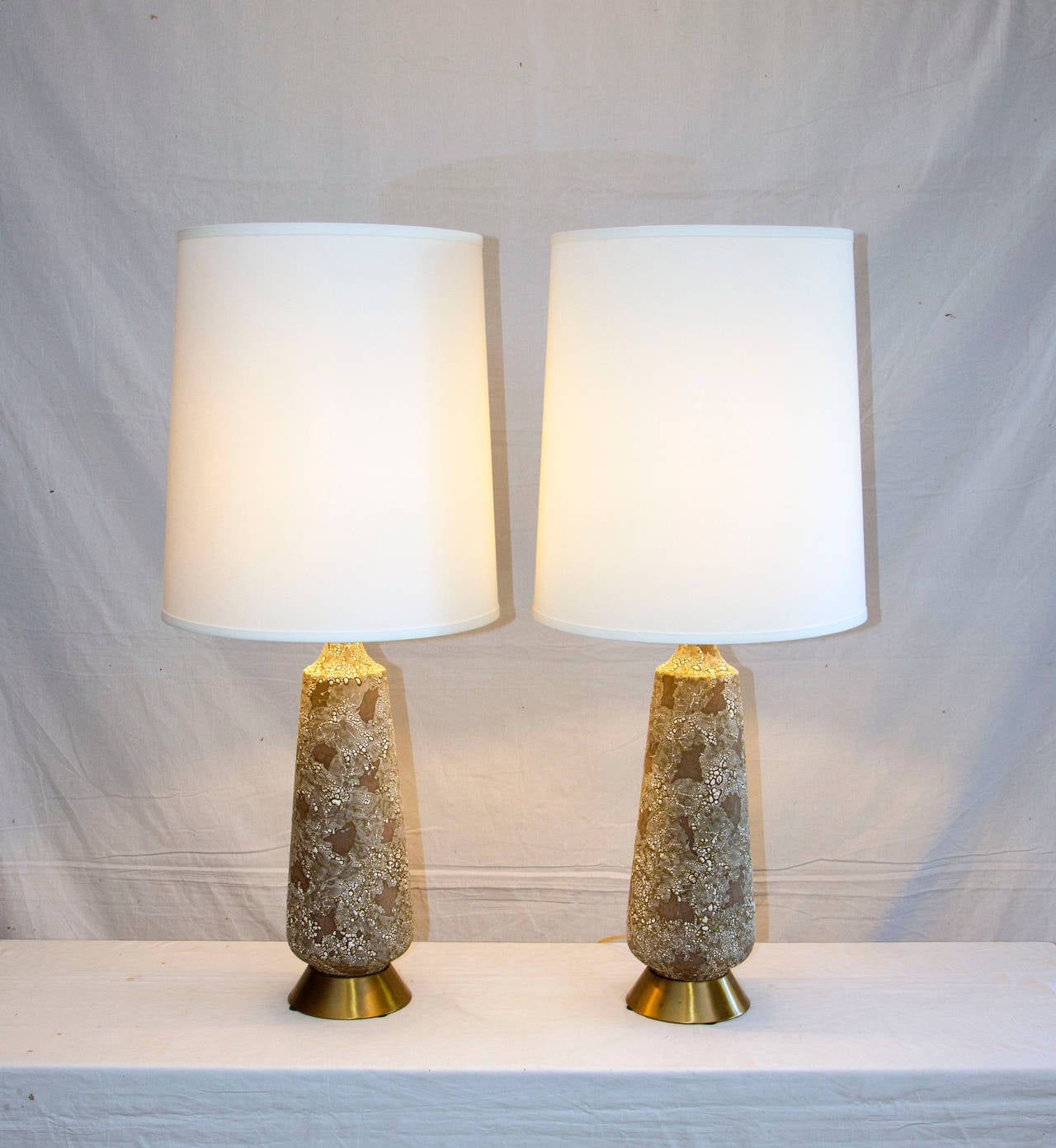 Nice textured ceramic base pair of lamps on the typical muted satin finish brass base. Colors include white, black, grey, greyish brown. Original manufacturers tags still attached where cord exits base "Navis and Smith Co. Chicago,