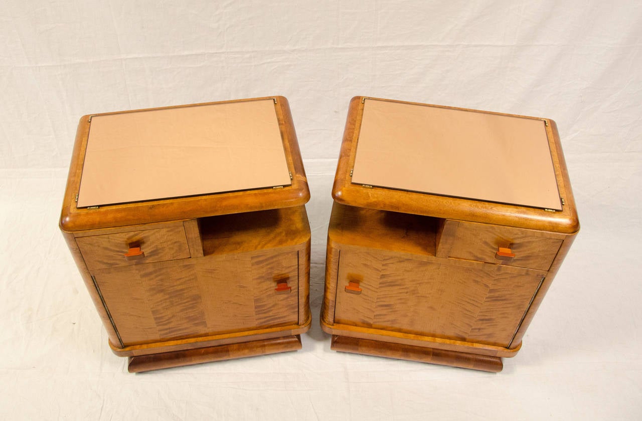 Very nice pair of French art deco night stands in figured maple. Accented by original peach mirrored glass and Bakelite drawer and cabinet pulls. Matching vanity with full length mirror being refinished.