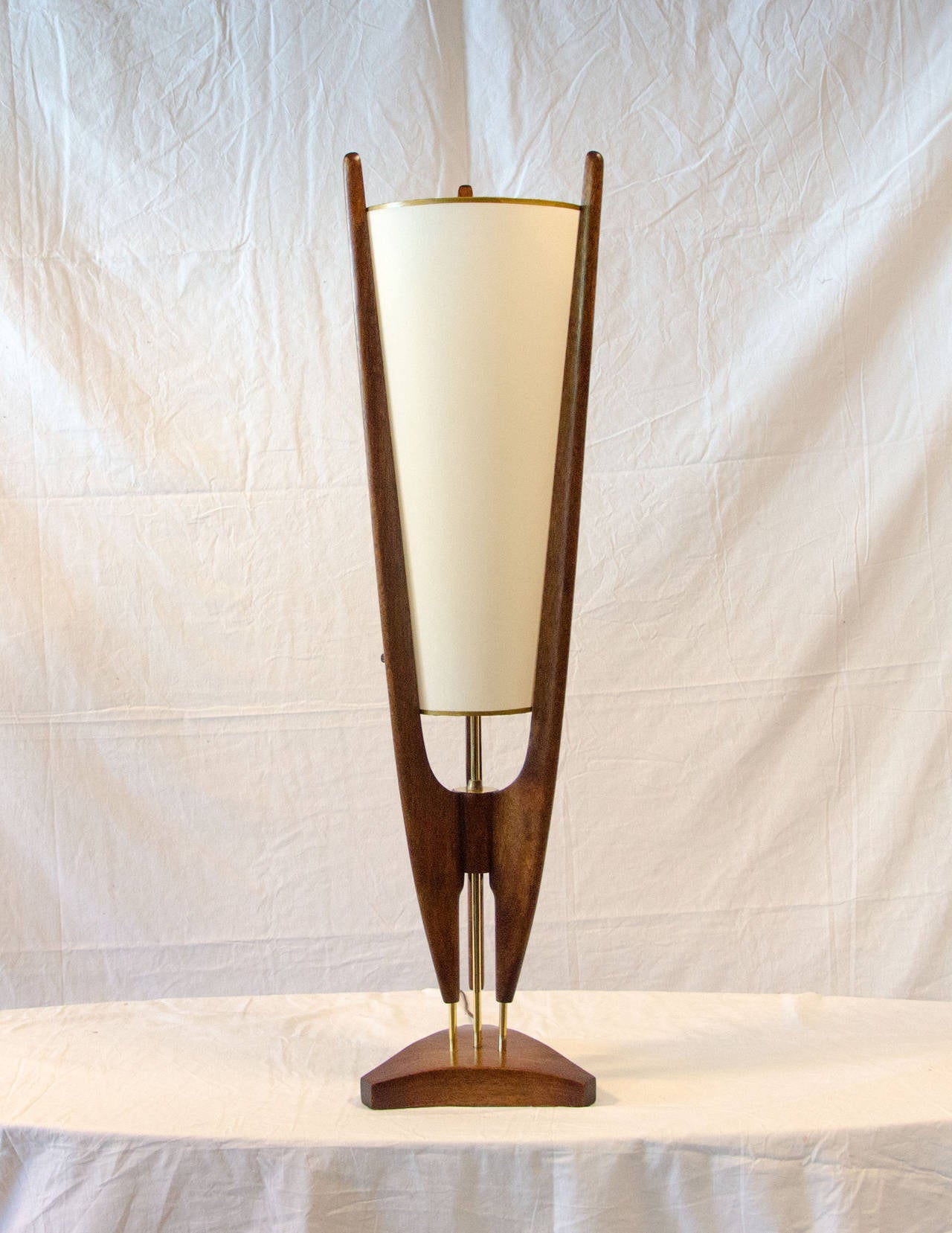 Very nice Danish style table lamp in brown mahogany with brass accents and a cone shaped shade fastened in the center of three uprights. There are two light bulbs at staggered heights, lit sequentially to give plenty of light. The shade has no burn