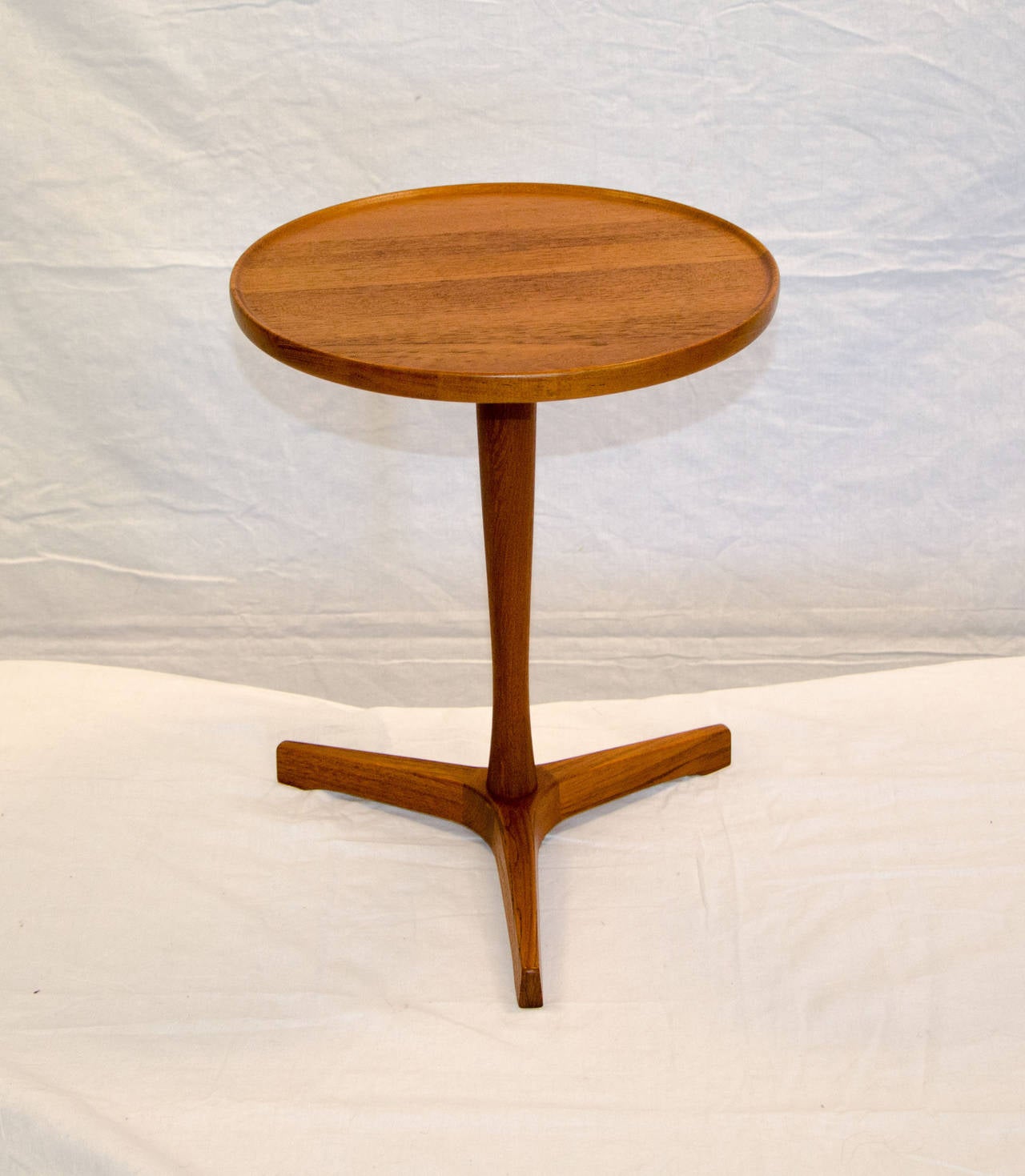 Useful small round tripod pedestal accent table designed by Hans Andersen, signed on flip side of circular top. The top and base disassemble for box shipping. The circular top is accented by a slightly raised edge.
