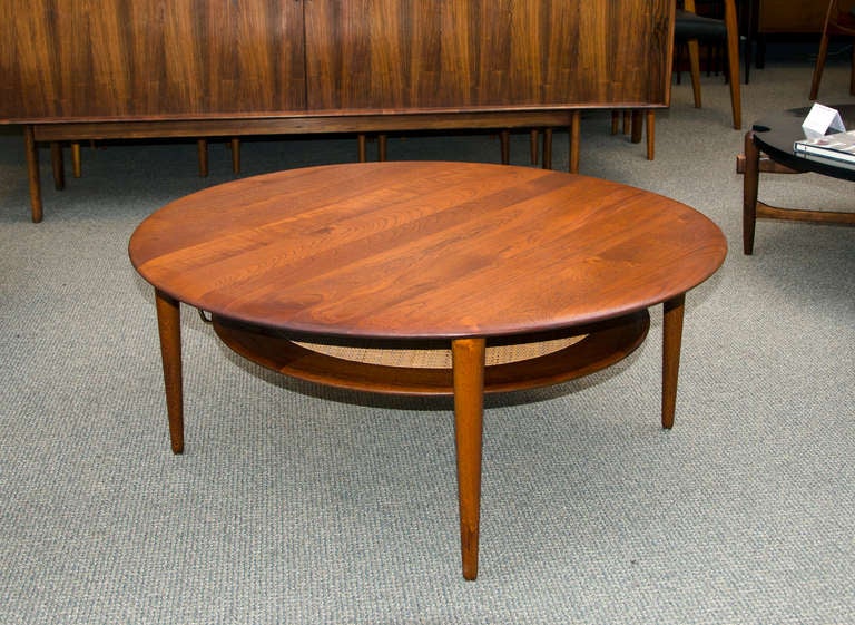 A very nice example of the iconic solid teak circular coffee table designed by Peter Hvidt and Olga Molgaard-Nielsen. The lower shelf has a caned insert supported by a thin wood ring, it is 10
