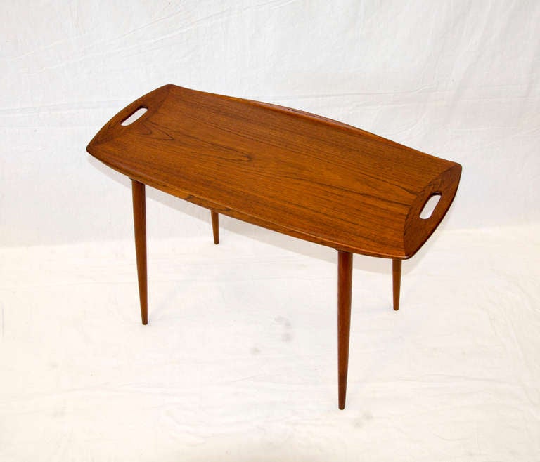This stylish tray table was once the largest of a group of three nesting tables. 
Rectangular/oval shape has a finger cutout at each end for easy moving. Upturned edges on both sides.