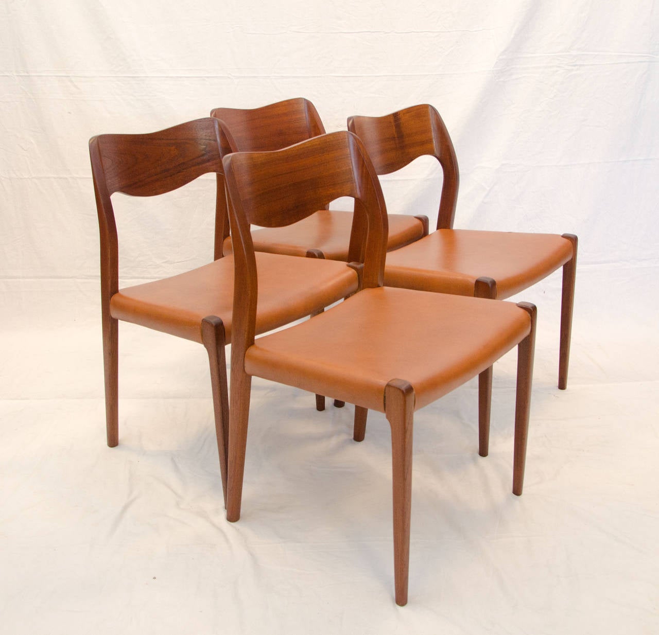 Set of four Danish Moller dining chairs with sculptural backs and original brown vinyl seats.