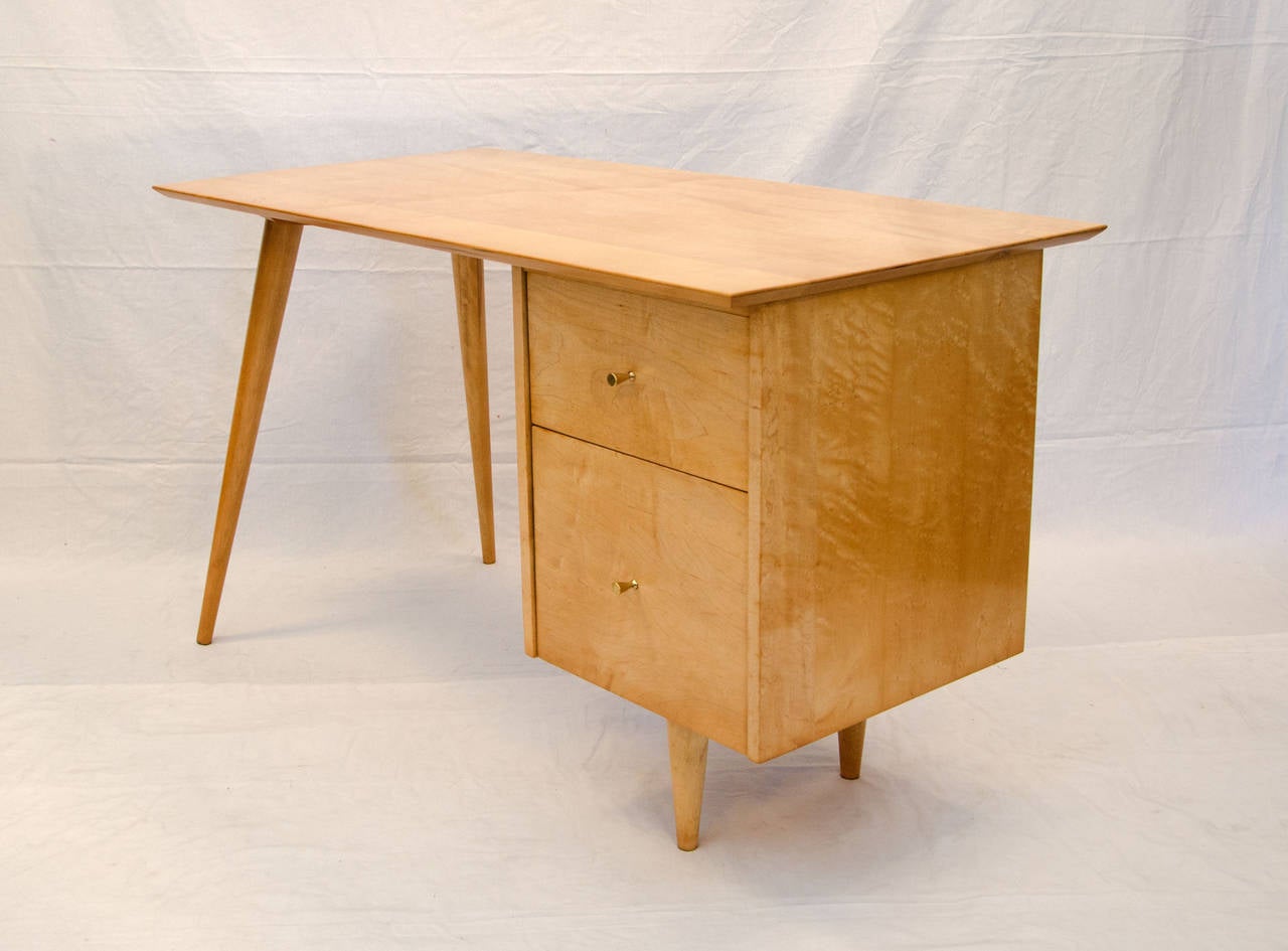 Solid maple medium size desk supported by drawers on one side and the signature angular tapered legs on the other. The top drawer retains most of the Planner Group label, bottom drawer is for filing. The desk is finished on the back side for center