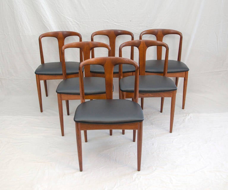 Beautiful sculptural Danish solid teak dining chairs. The Juliane model designed by Johannes Andersen. Faux leather seats are low maintenance and can be cleaned with a damp cloth.
