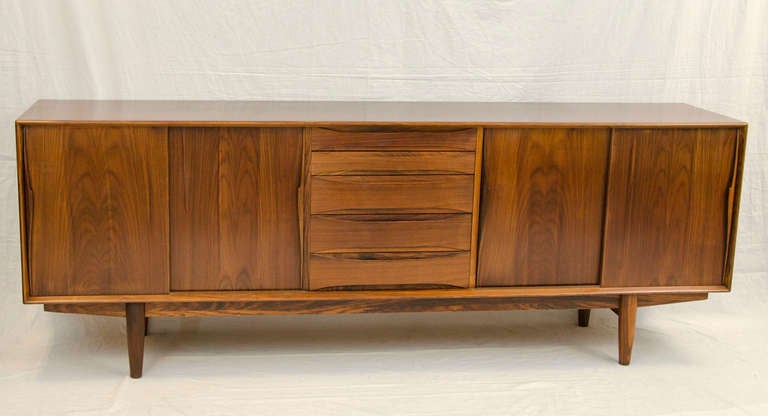 Extra length Danish credenza with two sets of sliding doors, a center storage drawer section, and adjustable shelves. Finished back allows for use as a room divider. Retains the Dyrlund paper label.