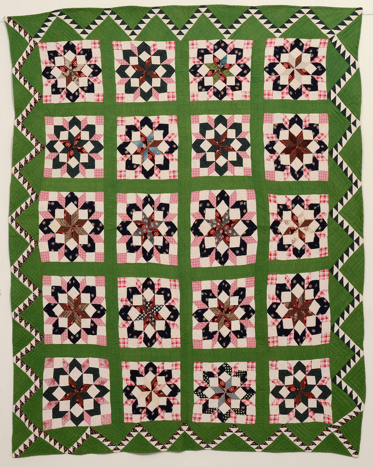 The use of color and fabric could not be better in this Carpenter's Wheel quilt. The green background beautifully sets off the deep indigo and rose tones while the pink diamonds give a bursting effect to each star. And who could ask for a better