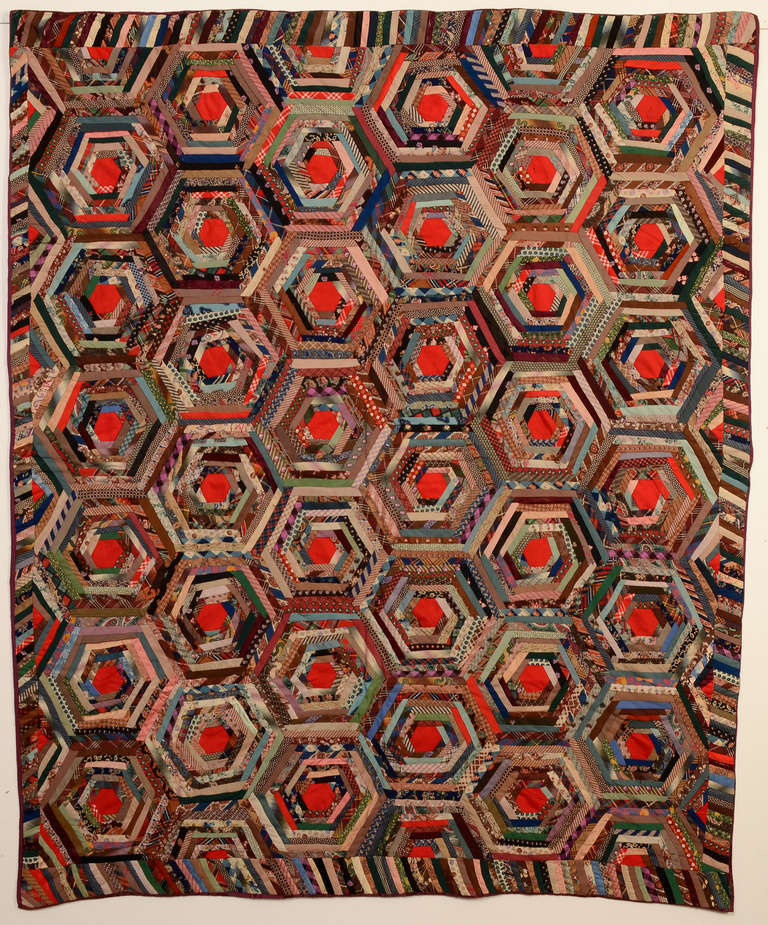 This is a terrific, complex version of a Log Cabin forming a rare spiderweb pattern. Made of a large variety of wool challis prints that have an unusual primarily blue/ green tone set off by the red centers. Nicely framed by the piano key border.