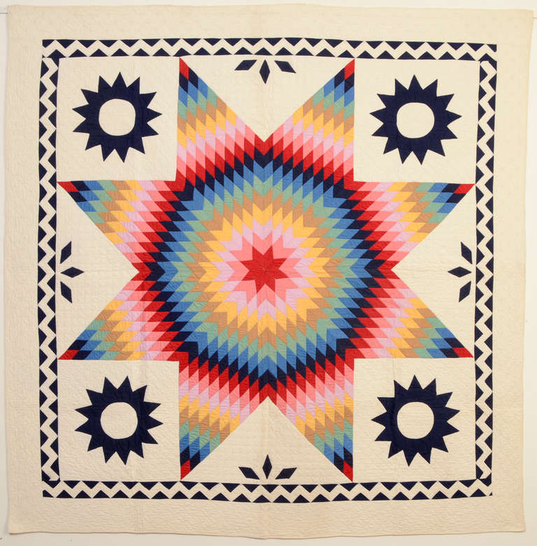 This Lone Star quilt is perfectly done in every way. It is well quilted including an unusual pattern of overlapping circles throughout the border. The piecing is well done with the ideal choice of the red color for the center. The corner suns are