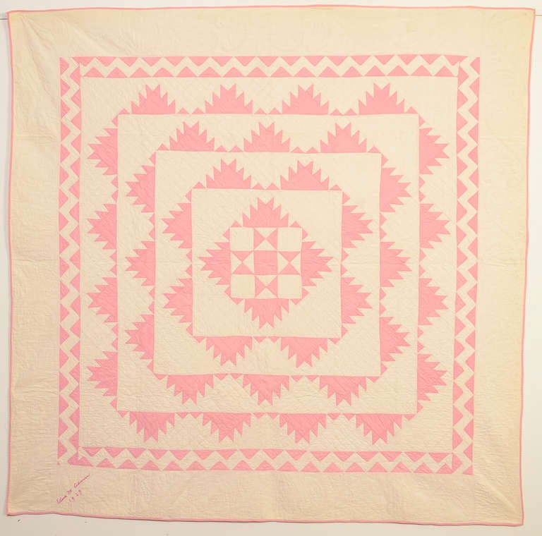 This is a beautiful example of the much sought after, Delectable Mountains quilt pattern. It is done in a pleasing soft shade of pink. The center forms an Evening Star pattern and it has a wonderful zig zag border framing all. Embroidered in a