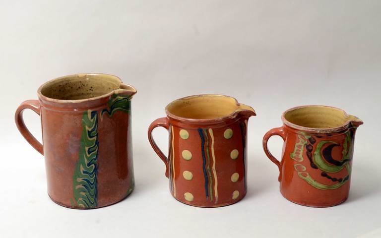 These three country pitchers, known as jaspe pottery, are from the Savoie region of France. They date to the late 19th - early 20th century. They are all solid enough to hold liquid but show some wear to the rims as is to be expected with