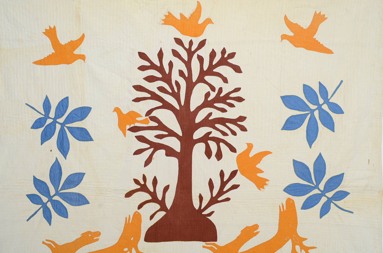 Ce quilt pictural extraordinaire dépeint des images à la fois féroces et amicales. En bas, des chiens poursuivent des cerfs, tandis qu'en haut se trouve un arbre de vie entouré d'oiseaux, dont l'un pourrait être une colombe. Il est dommage de ne pas