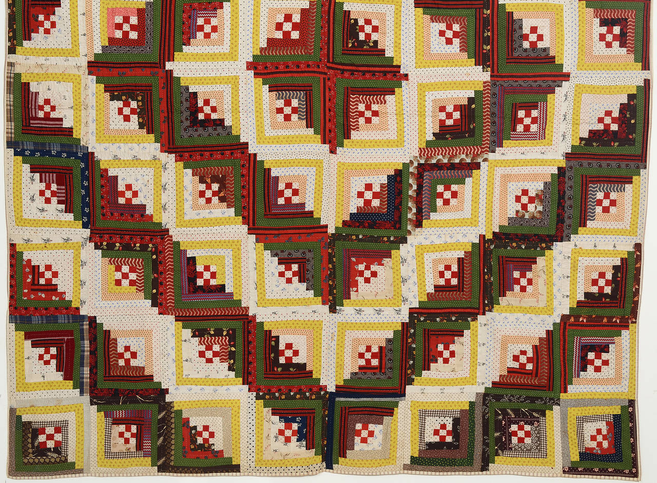 This classic barnraising log cabin quilt has a charming twist. The centers are all nine patches. They are done in solid reds which make them really pop out against the prints of the rest of the quilt. The prints include conversations with anchors,