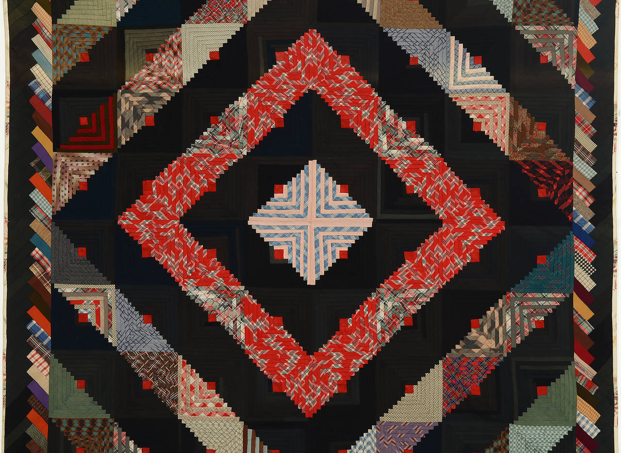 This bold barn raising log cabin quilt beautifully combines patterned fabrics to create added interest to the eye. The use of light fabrics in the center diamond draws your eye immediately to this focal point while the many additional prints lead