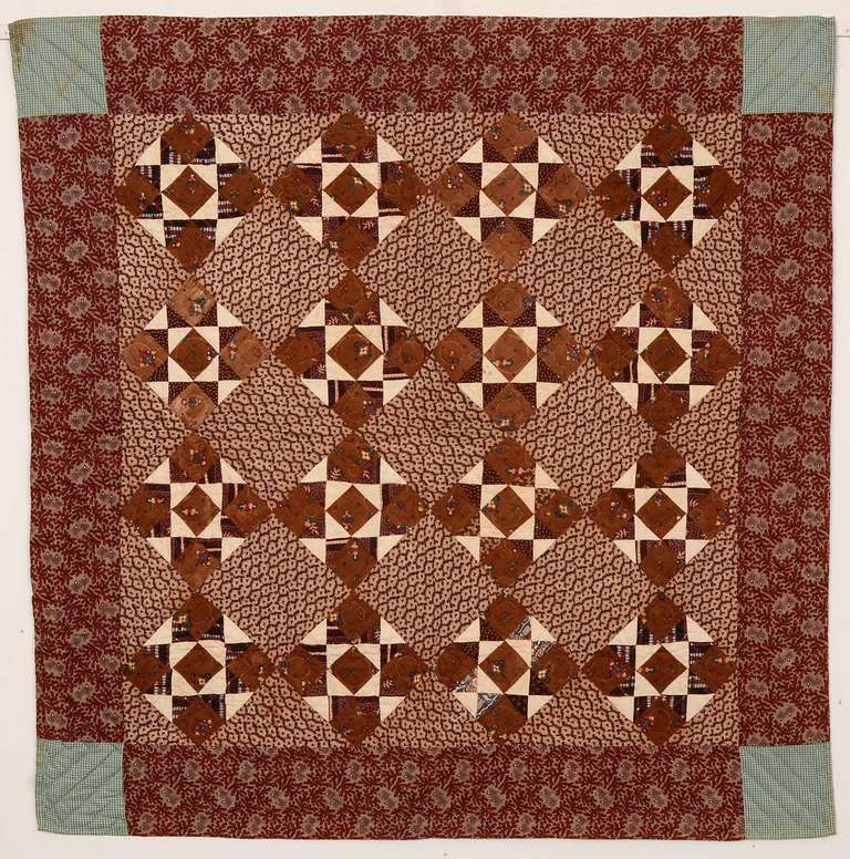 What initially appears to be a straight forward Evening Stars crib quilt actually forms an additional pattern. The consistent use of the same white with printed brown triangles forming the points of the stars also makes an Hourglass pattern