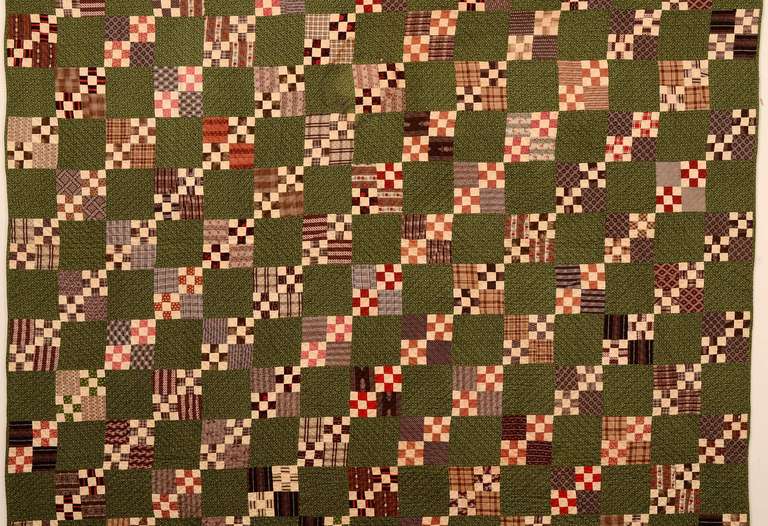 This four-patch within a nine-patch quilt makes an additional pattern of Straight Furrows with the solid white blocks consistently placed to form diagonal lines. The deep green calico background and many brownish colored printed fabrics form a nice