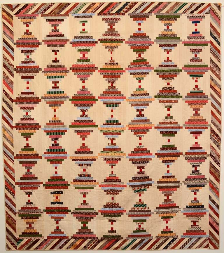 This Courthouse Steps Log Cabin quilt is unusual because of the use of solid white blocks with the calico prints. The piano key border is a nice way to continue the strips of the Log Cabin while offering a variation in the pattern. The center of