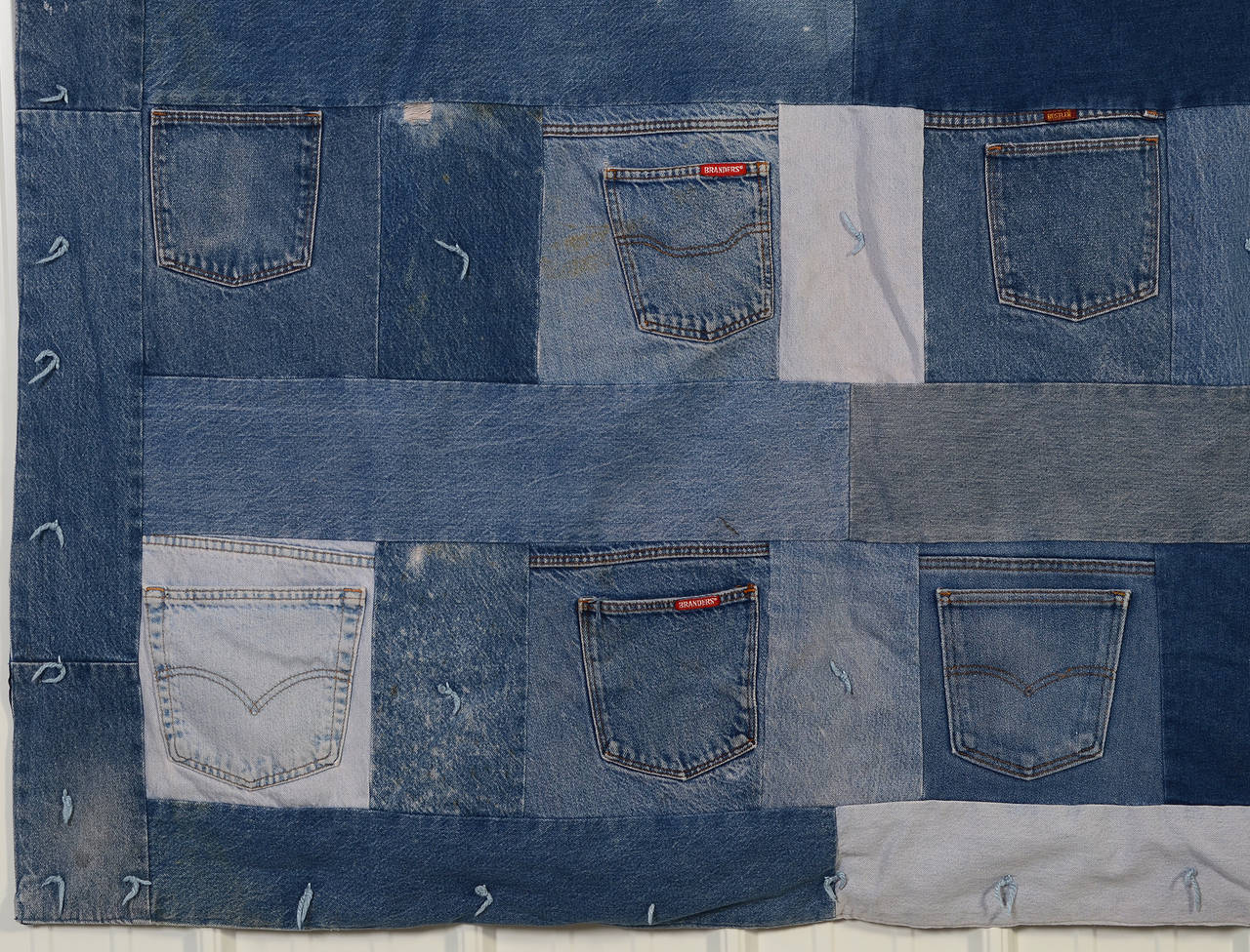 This whimsical denim comforter has a rear pocket from blue jeans in each block. The variety of colors and shapes of the denim blocks and pockets makes for an interesting abstract composition. Backing is plaid cotton flannel.