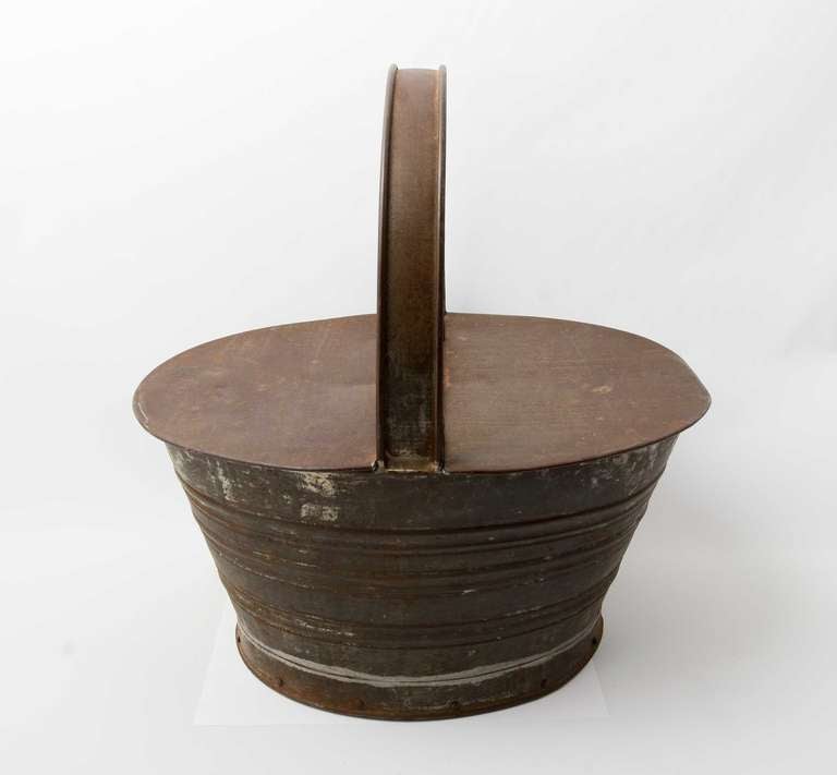 Handmade basket of heavy tin with a wood bottom. The hinged lid opens from both sides. Measures 18