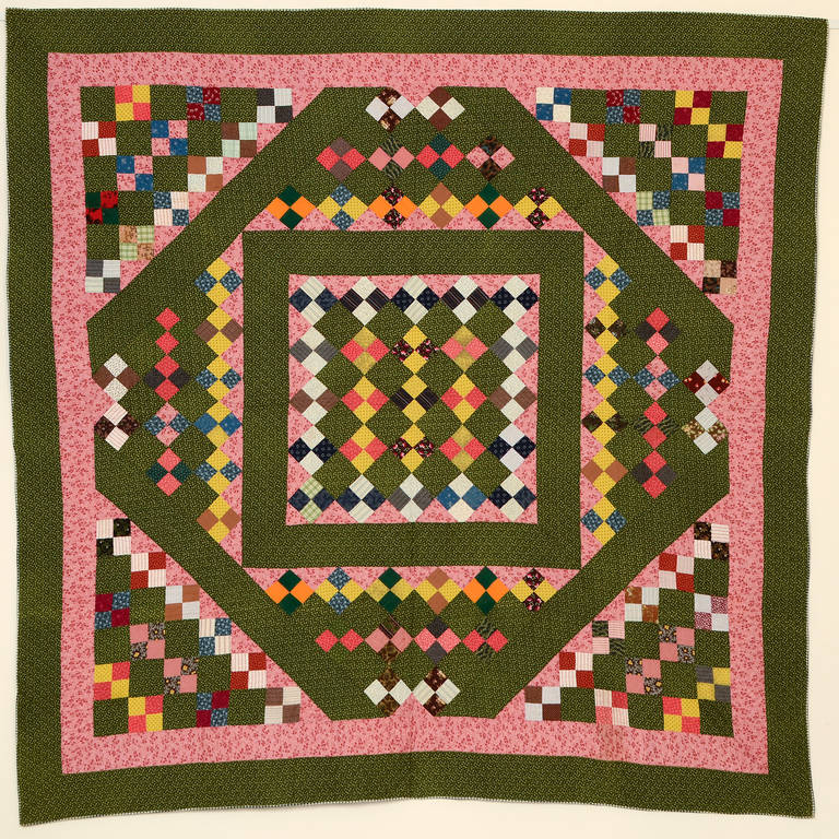 This four-patch quilt is certainly one of a kind. The overall pattern is something of a square within a diamond but it has a completely different appearance as it is filled with four-patch patterns on point and on square. Nicely quilted with