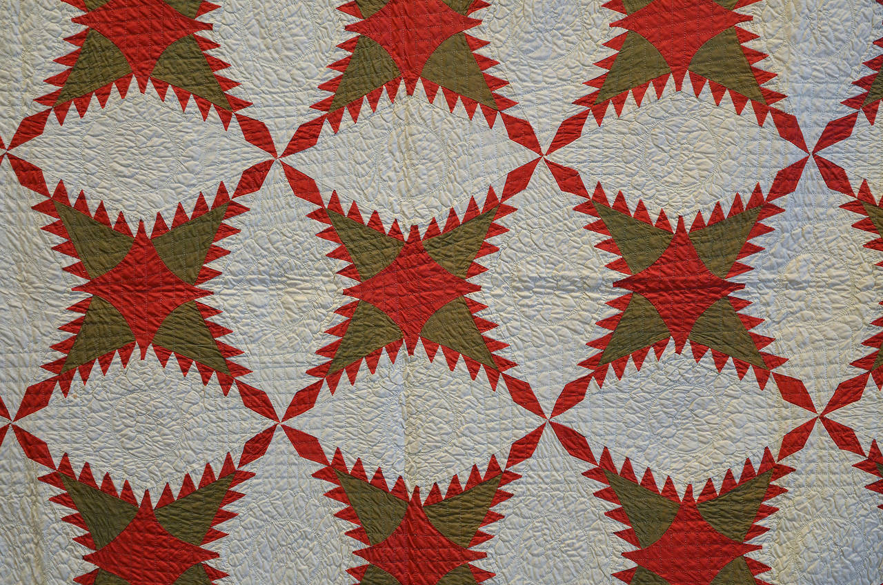 This finely made Pine Burr quilt has an unusual amount of swirling movement. The white off blocks form circles around the four point stars and can also be seen separately as lozenge shaped blocks. It is both well pieced and quilted. The quilt is