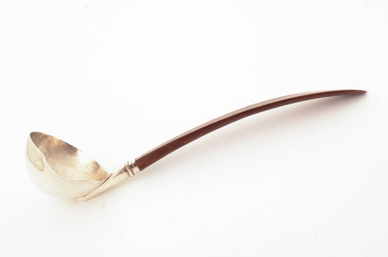 Elegant silver ladle with an wood handle by silver master, William Spratling. The inside of the bowl shows the hand hammer marks. It measures 3 1/2