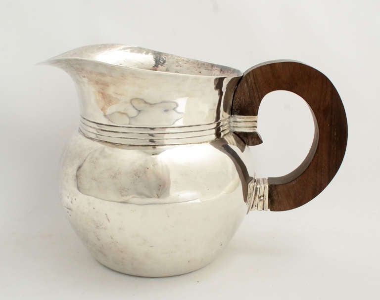 This bulbous, elegant pitcher by William Spratling is known as his Ranch design. It combines a sterling silver body with an ebony handle. The outside is smooth with hand hammer marks wonderfully evident on the inside. Measurements are 6 1/2