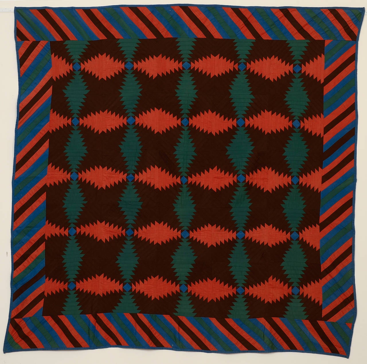 This powerful windmill blades (aka Pineapple) log cabin quilt is unusually sophisticated in its use of color. The rich chocolate brown, salmon, blue and green work perfectly together. The piano key border is a clever continuation of the shape of the