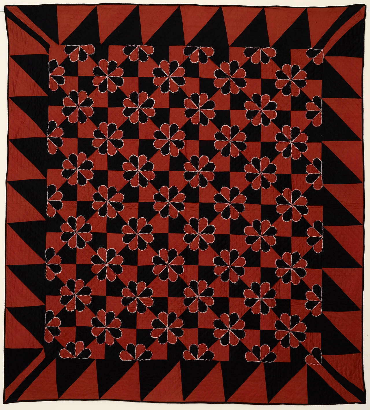 This Mennonite Hearts and Gizzards quilt is made with a rich combination of colors. It is black with what can best be described as a rosy terra cotta. Embroidered stitching in white lightens the entire piece. The wide triangle border is a nice