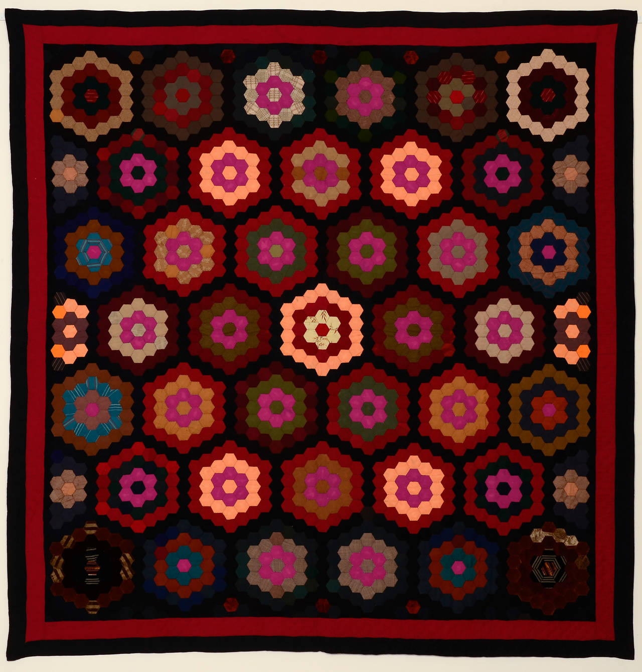 This Mennonite hexagons quilt makes a stunning composition. The colors are beautifully arranged with the peach color blocks in all the right places. The red and black borders repeat the same fabrics within the quilt. The quilt is almost entirely