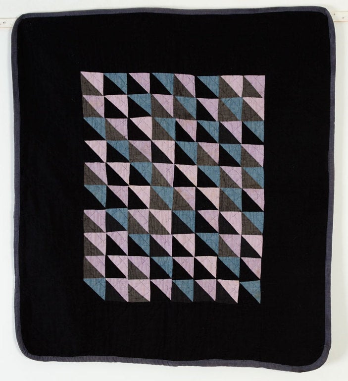 This Thousand Pyramids Ohio Amish Crib Quilt has a wonderful arrangement of light and dark fabrics. The light blues are well placed to add to the overall diagonal pattern. Several black fabrics are used. The border is quilted with diagonal lines and