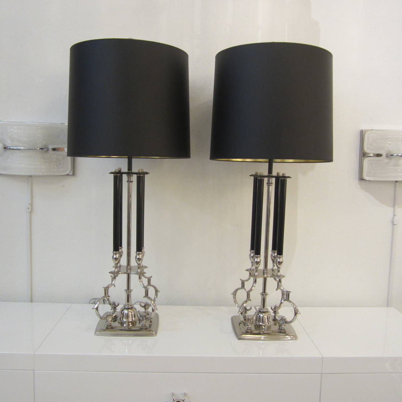 Pair of tabletop lamps featuring nickeled, scrolled metalwork and black painted metal columns with double light bulb sockets. Newly rewired and appointed. Original ring finials included. Sold as a pair without the shades.