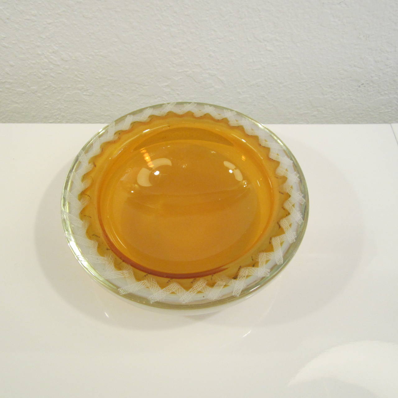 Handblown Murano glass console bowl with golden center and a white latticino boarder. The outer glass is opalescent with an almost pinkish hue.
Very attractive.