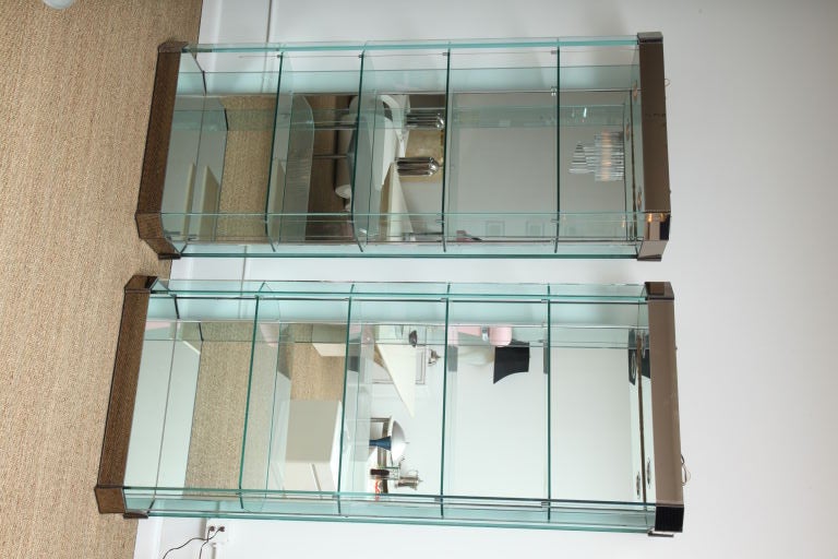 Pair of open Vitrines featuring multi tiers of hexagonal glass mounted by front cables with glass frame, silver mirrored backs, and bronze mirrored crowns and base. Lighted with two sockets each with side push on/off buttons.