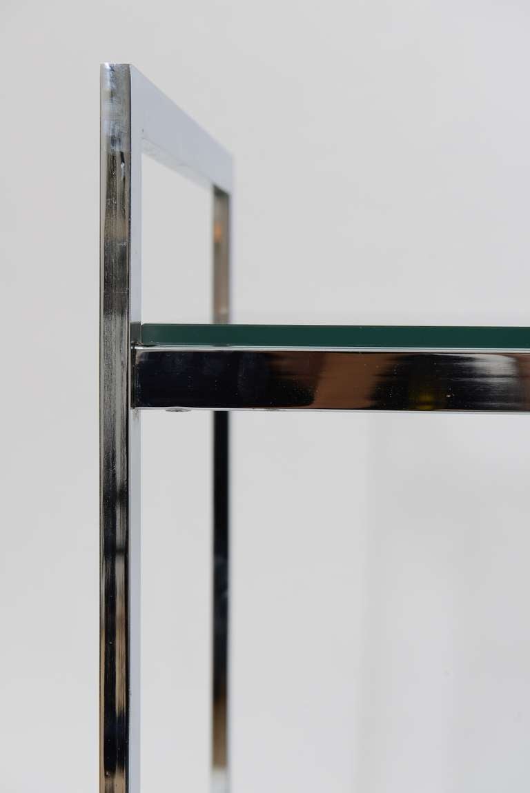 Elegant clean line bar cart in polished chrome with two tiers of glass shelves. Smooth rolling wheels.