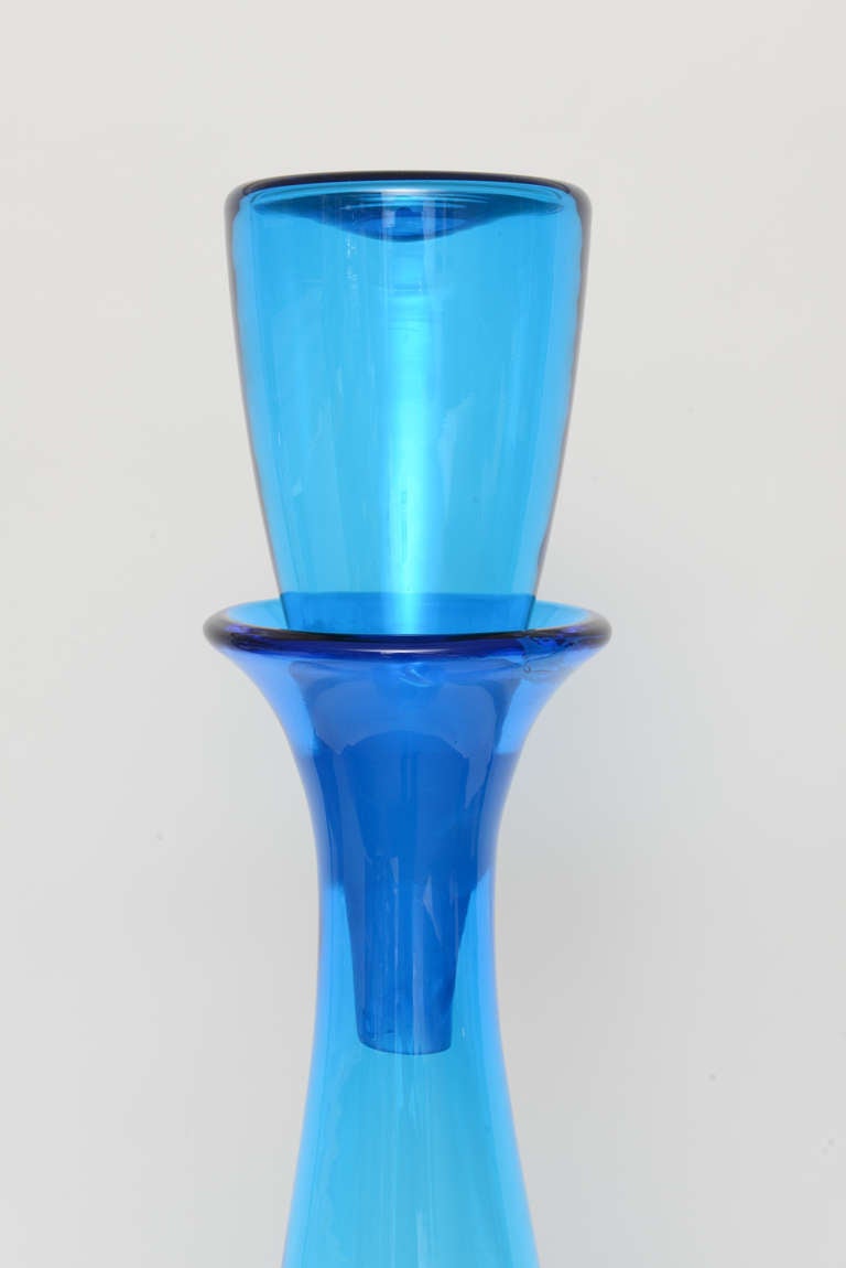 Hand blown tall floor decanter with original matching stopper. This decanter or decorative bottle or vase stands tall enough to occupy it's own space be it in a corner or as a solo display object d'art. Fascinating on a tabletop or cabinet.