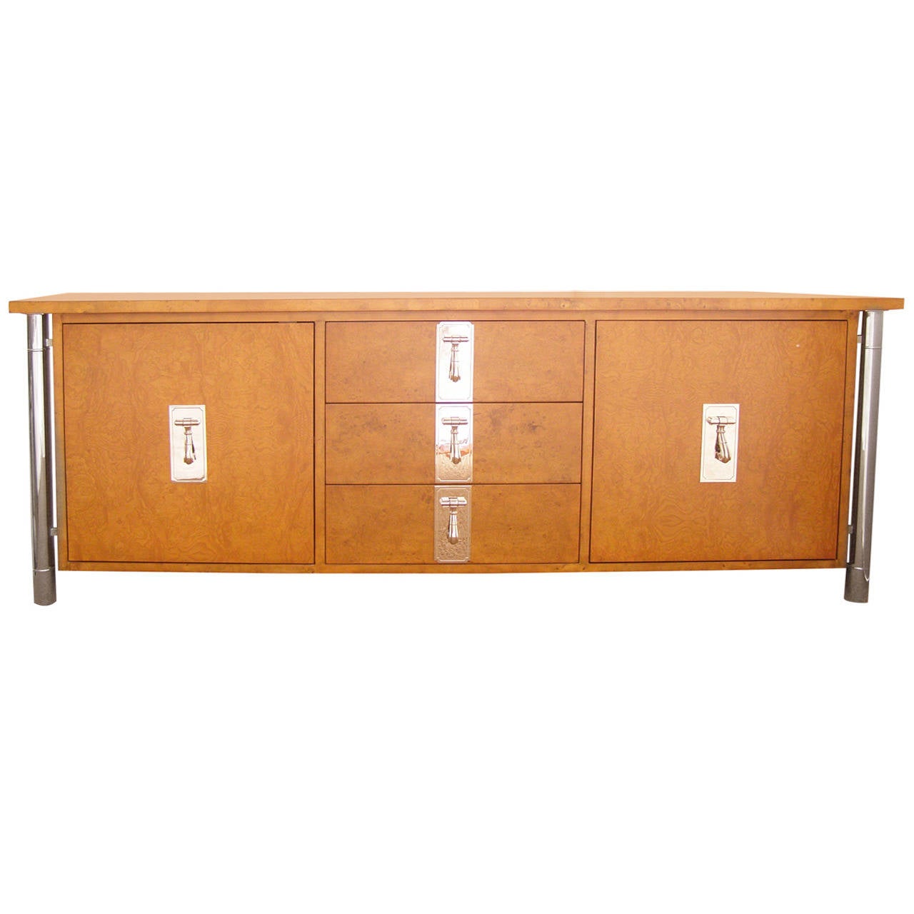 Exceptionally well made Mastercraft credenza in burl wood with 2 nickeled columns on either side and heavy nickeled drawer and door pulls.  Excellent storage capacity with 3 deep and wide drawers and cabinetry behind the doors. Finely refinished