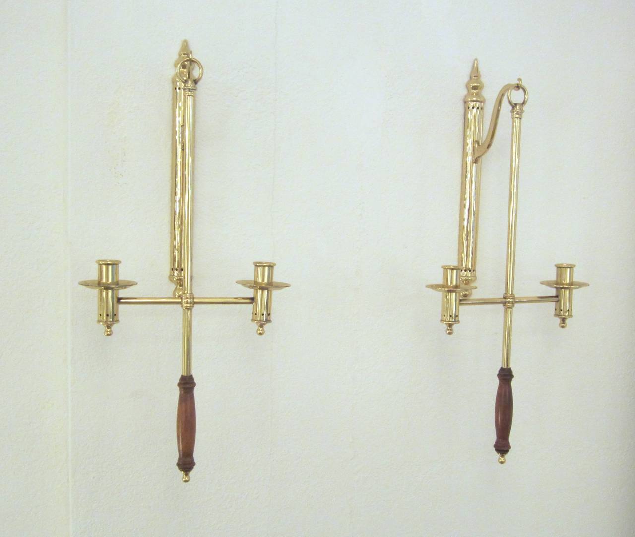 Wonderful pair of polished brass hanging candle sconces with wood handles. They hang from vertical back plates also in polished brass and hold two candles each and are removable to walk through the darkened areas of home. Purchased in West Virginia.