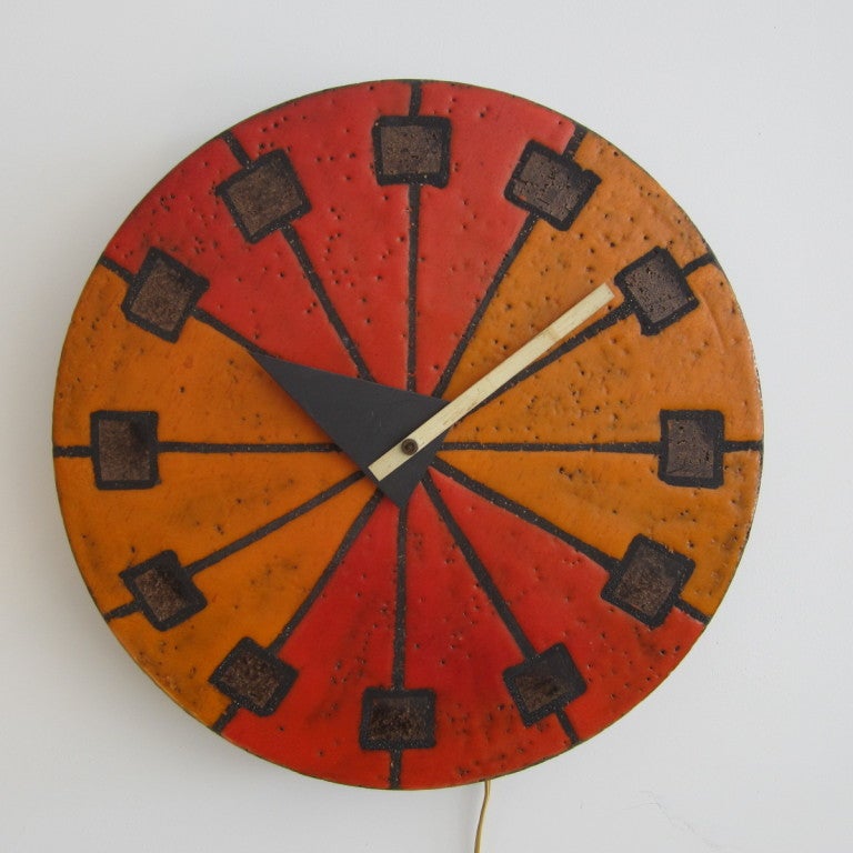Superbly made modernist ceramic clock in shades of orange, brown and gold. Ceramic is molten with glaze exposing the lava-like texture. Clock is wired and in working order with original sticker on back. This clock was put together (manufactured) in
