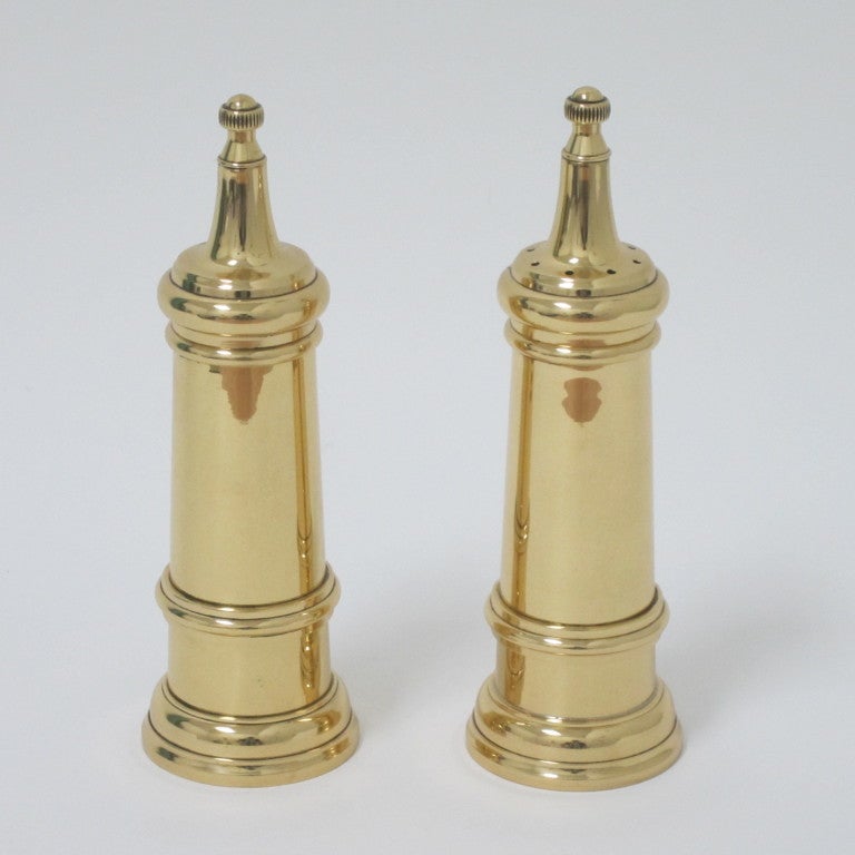 Elegant pair of salt and pepper mills fashioned in high polished brass. Salt shakes from the top while pepper is cracked through the mill. Made in Italy inscriptions.