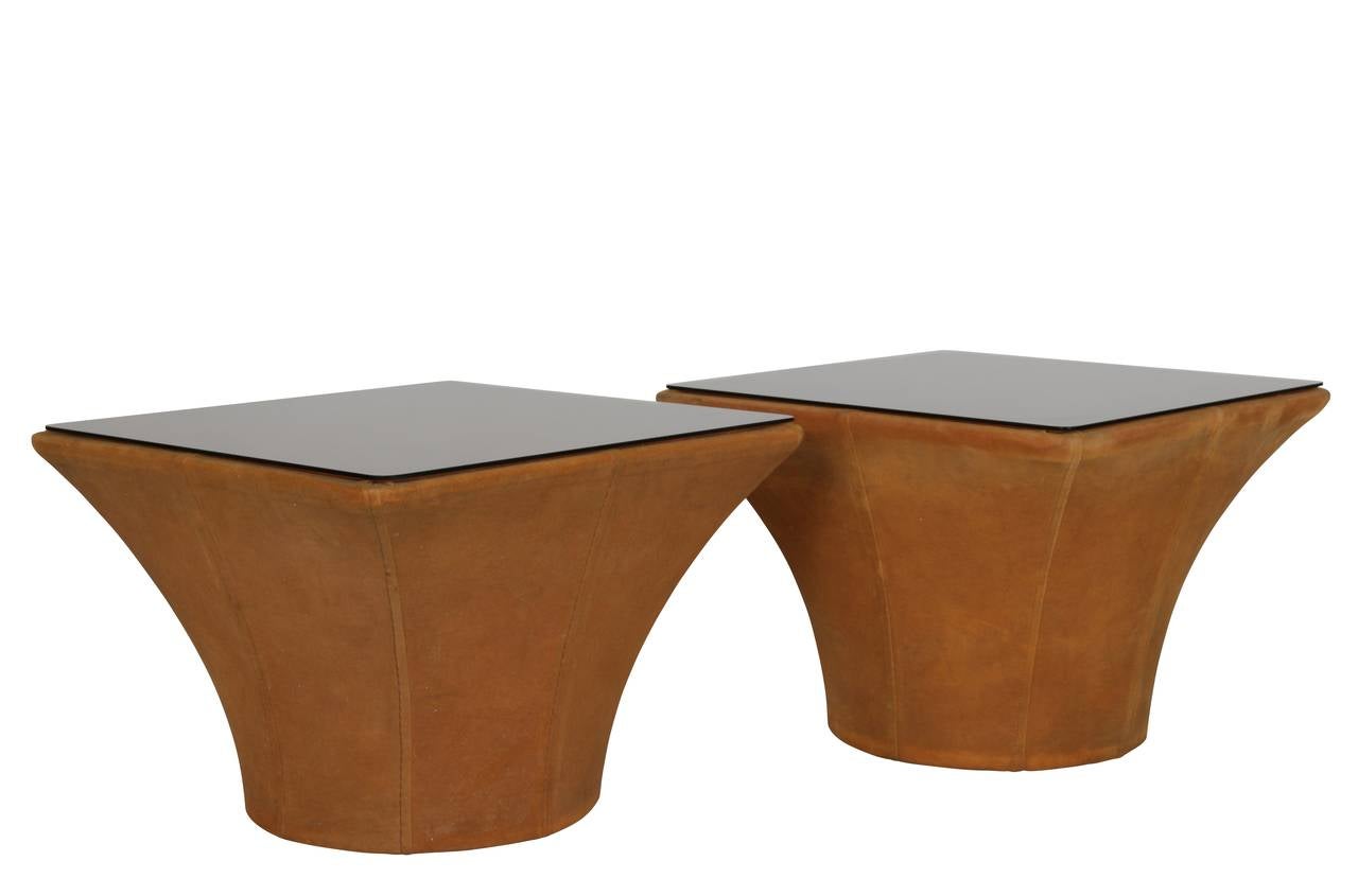 Pair of low side tables fashioned of bronze colored suede cloth in the shape of columns with bronze glass tops. Meticulously sewn, nailed, and stretched over wooden frames. Fantastic original condition.