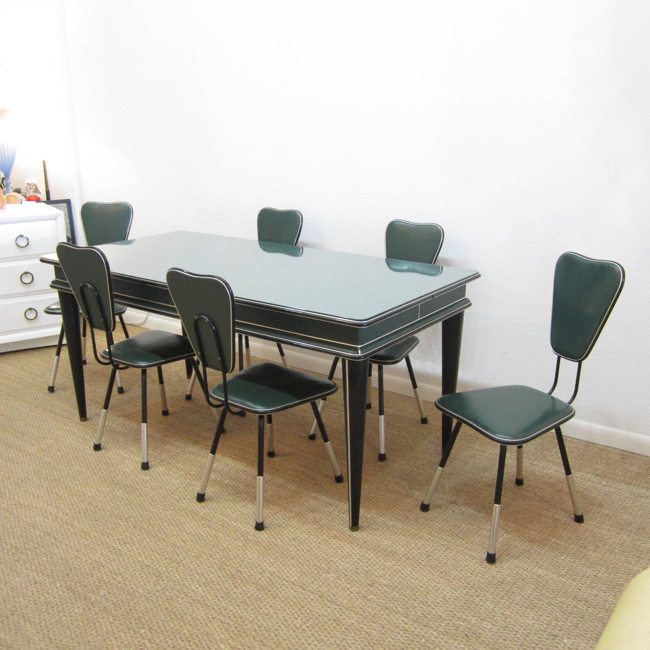 Fantastic dining table covered in green pebbled vinyl with coordinating black pebbled vinyl tapered legs all with aluminum trim. The tabletop has removable glass top and the legs taper to a thin point.
The matching chairs are in green and black