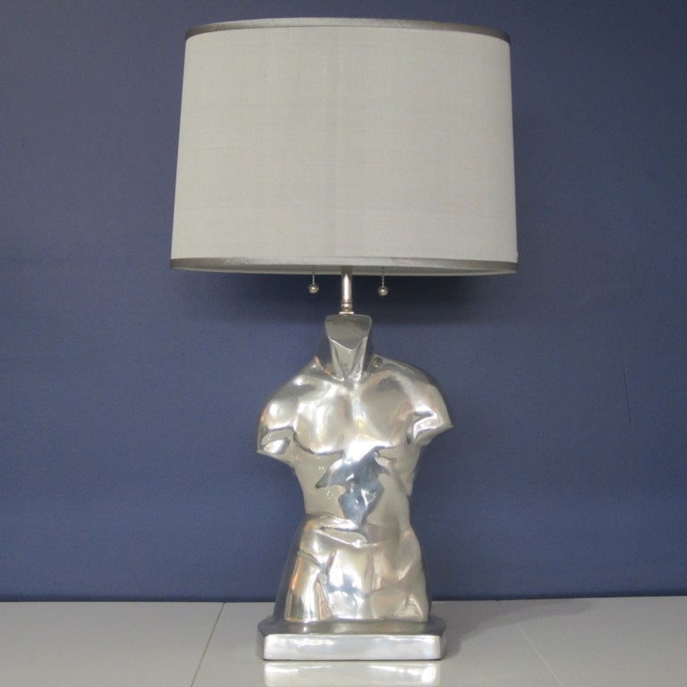 Fantastic male torso lamp in polished metal featuring double sockets each with pull chain. Very well made with four-way adjustable socket angles. Original spherical metal finial on height adjustable rod. Sold with or without silver Dupioni silk