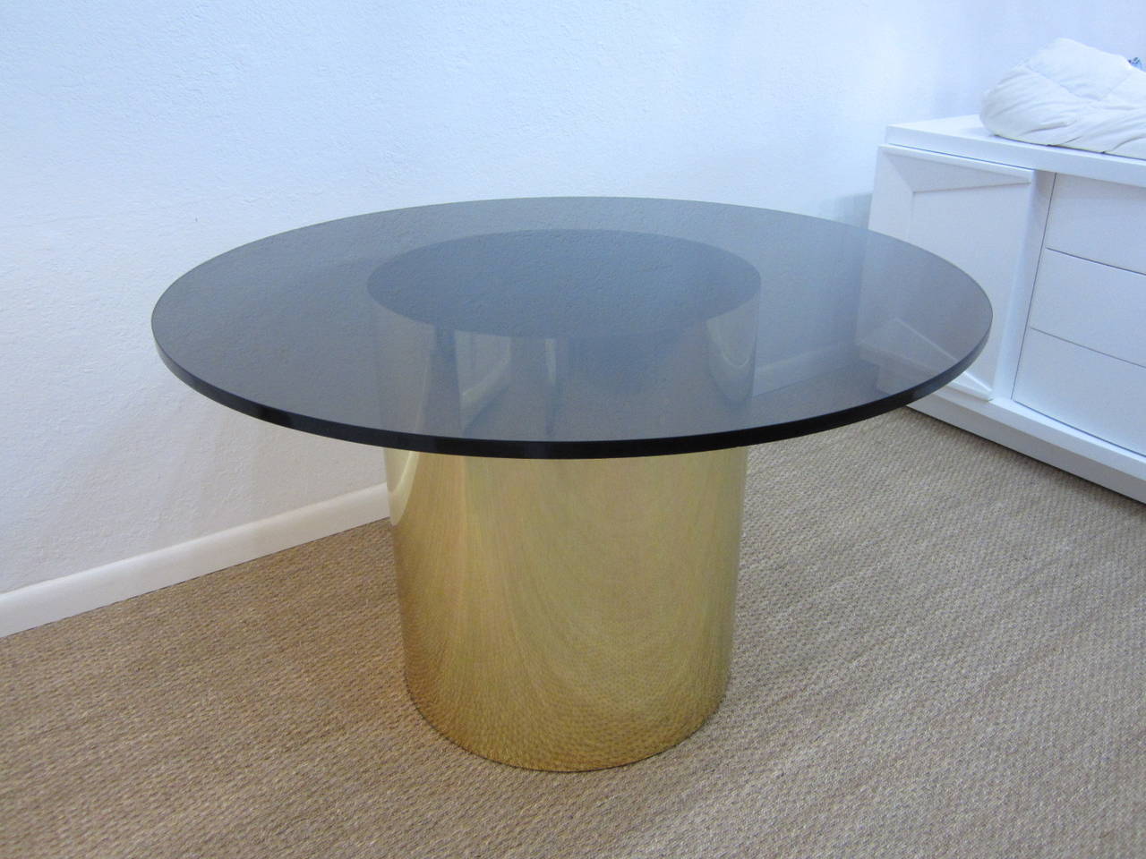Round drum table wrapped in brass with a thin matching vertical brass strip covering the seam. The 48 inch round top is a 3/4 inch thick amber glass with several tiny flea bites on the edges which have been smoothed over and do not interrupt the