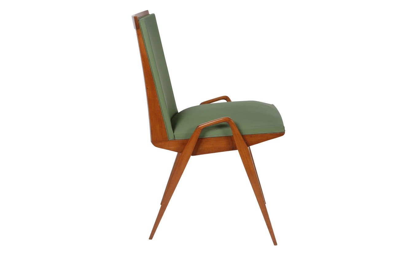 Set of eight dining chairs with frames made of pear wood and maintaining their original French ribbed vinyl-covered cushions. The legs and arms are magnificently integrated in one swoop and terminate with a fine tapered point. The seats are