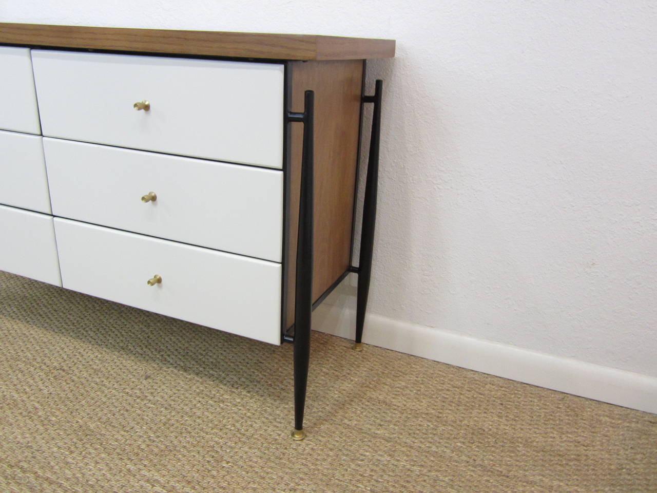 Wonderful three-tone chest of drawers with natural wood top and sides complimented by off-white drawers. Body is mounted on black iron four-legged frame with tapering legs terminating with gold-washed brass feet. Original bullet drawer pulls in