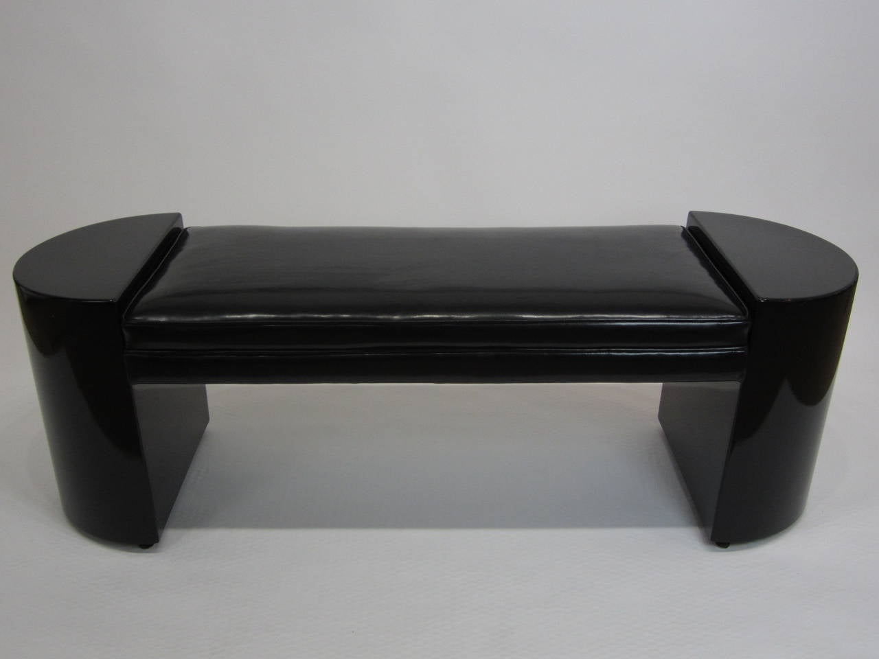 Beautiful gloss black lacquered Demilune bench with black patent leather cushion. Fabulous elongated design with centre cushion. Sides are composition and have great adjustable levelers on bottom. Shows minor wear commensurate with age.
