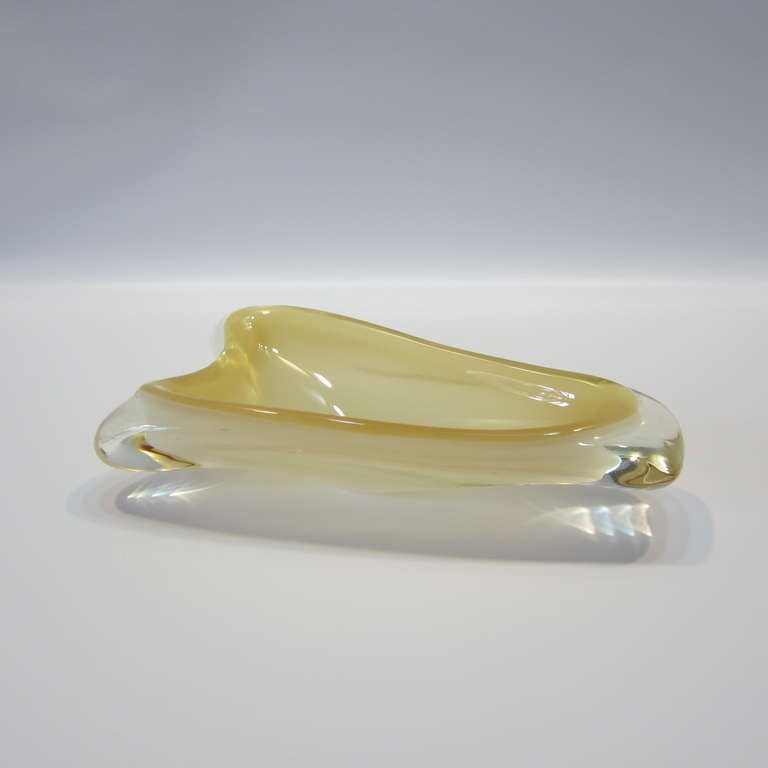 Midcentury handblown Murano glass dish in pale gold with amber hues surrounded in clear glass. This dish is a period design and maintains its original sticker on bottom.