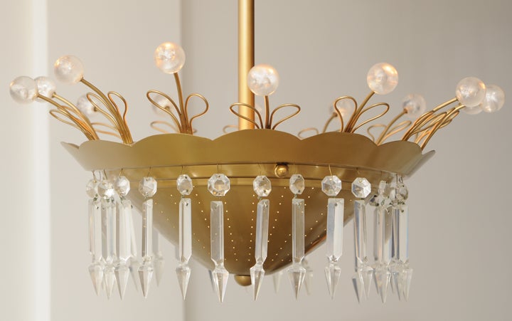 Chandelier fashioned of perforated and scalloped brass with flared top extenders with heart-shaped twisted and turned brass piping that terminate with lucite spheres. Dangling crystals hang around the perimeter of this 1950s period chandelier. Great