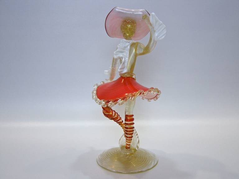 Venetian courtesan figure in handblown Murano glass with a lot of gold flecking known as aventurine. Scalloped hem is applied glass on top of glass and this and this type of appliqué is found throughout the figure. 
A beautiful example, by master